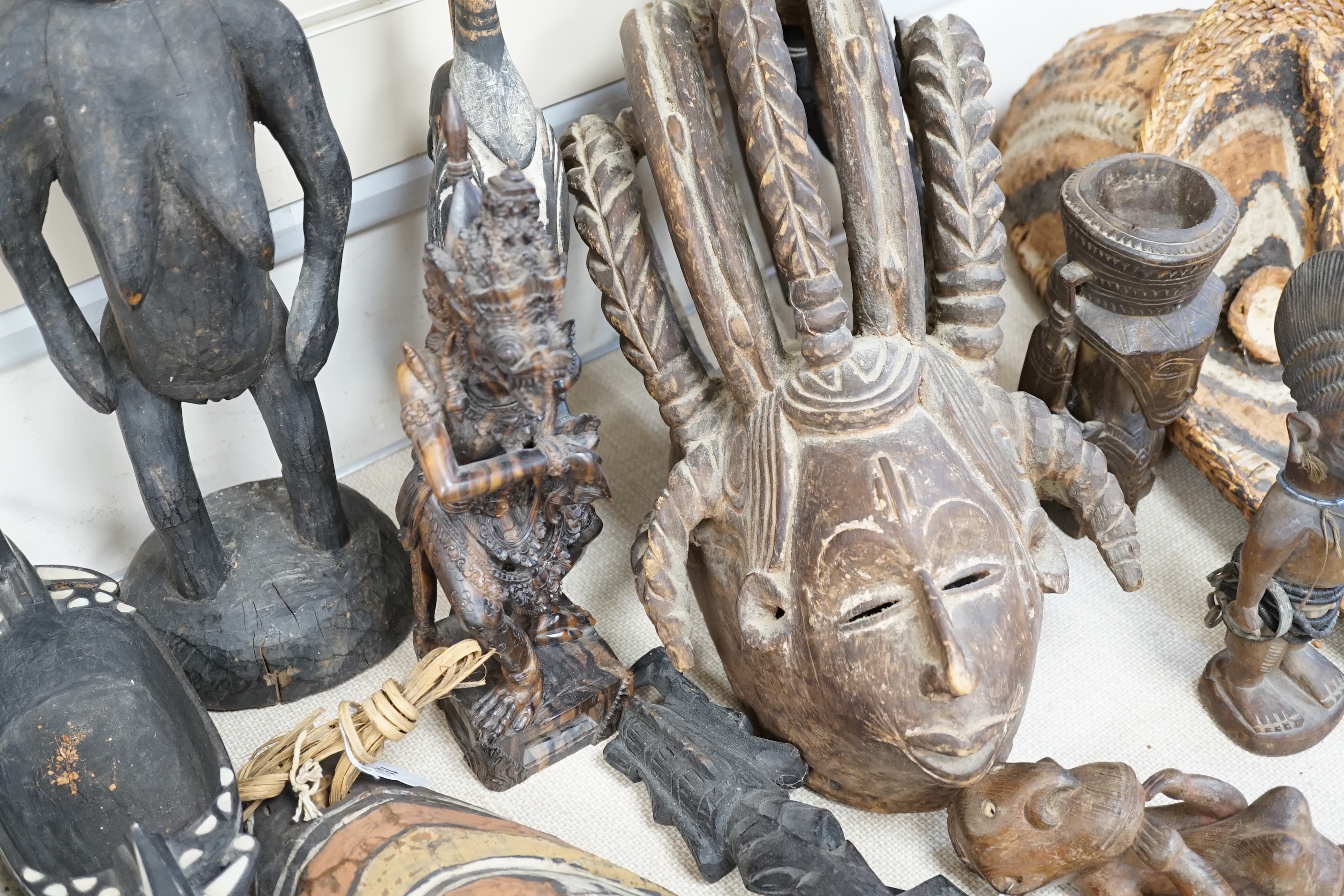 A collection of tribal carvings and masks mostly from Papa New Guinea, largest painted straw mask 86cm high